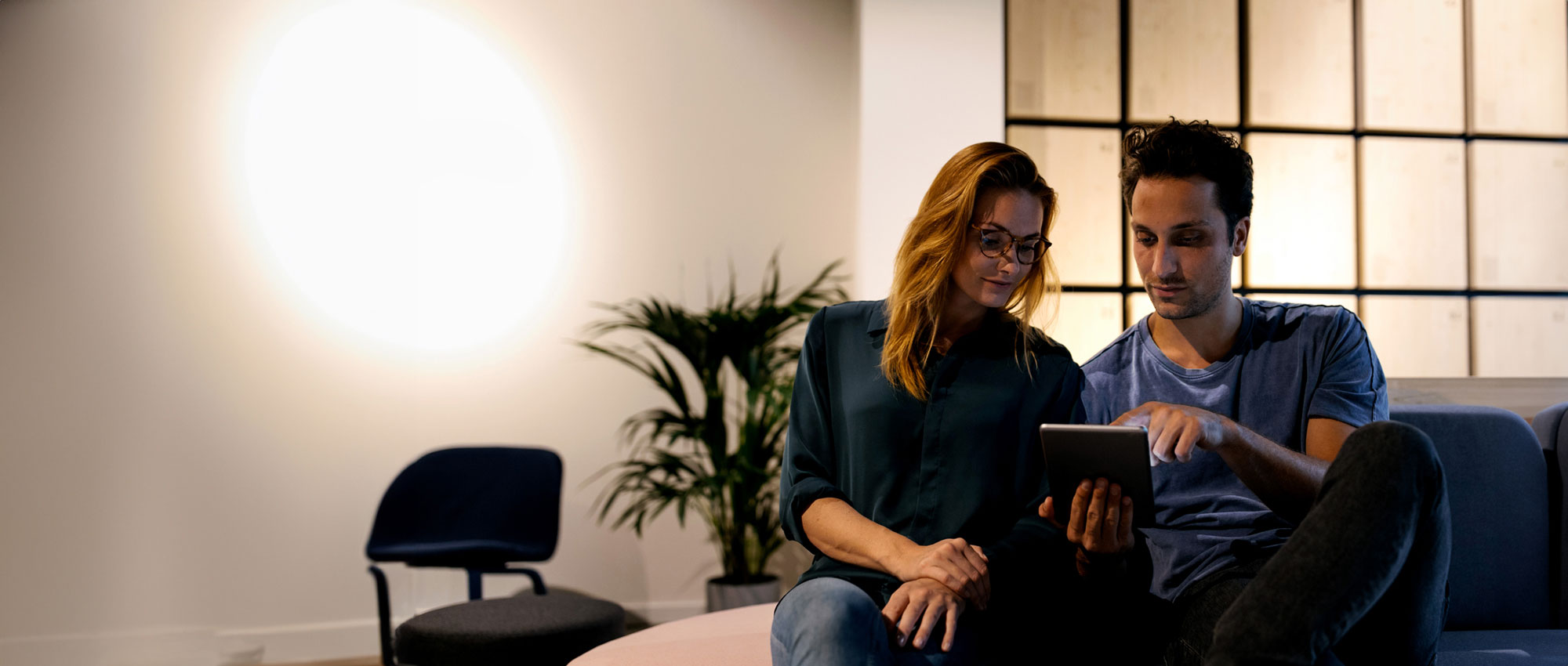a woman is sitting at a table with a towel wrapped around her head and a little girl sitting on top of her while eating a sandwich and looking at a laptop computer
